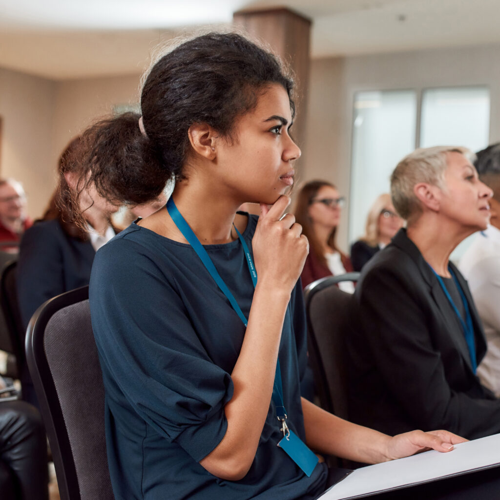 AdobeStock_334001464_Preview Young woman listening to a presentation