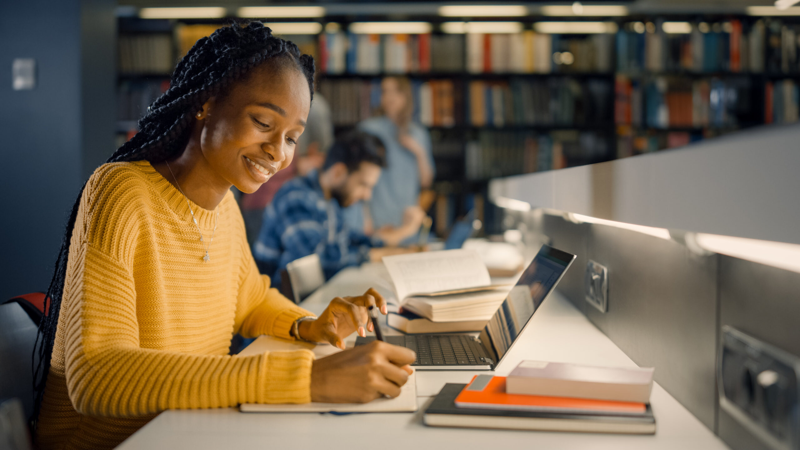 Black Girl uses laptop and writes notes